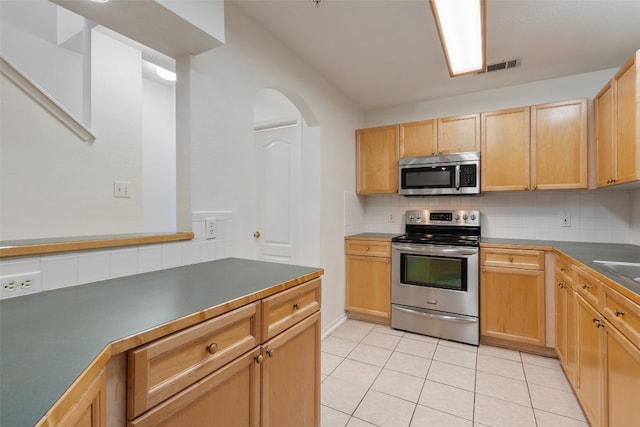 kitchen with light tile patterned floors, light brown cabinetry, appliances with stainless steel finishes, and tasteful backsplash