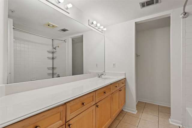 bathroom with tile patterned flooring, vanity, and tiled shower