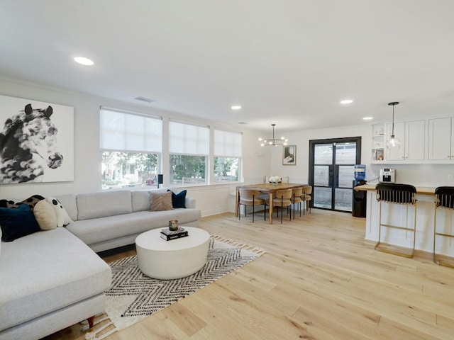 living room featuring a notable chandelier, light hardwood / wood-style floors, and a wealth of natural light