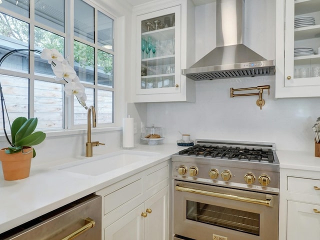 kitchen with sink, backsplash, wall chimney range hood, white cabinetry, and stainless steel appliances