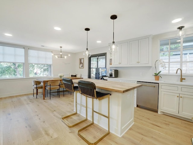 kitchen with dishwasher, light hardwood / wood-style flooring, hanging light fixtures, and white cabinetry