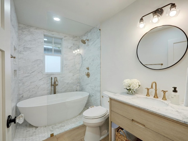 bathroom with a tub to relax in, vanity, and toilet