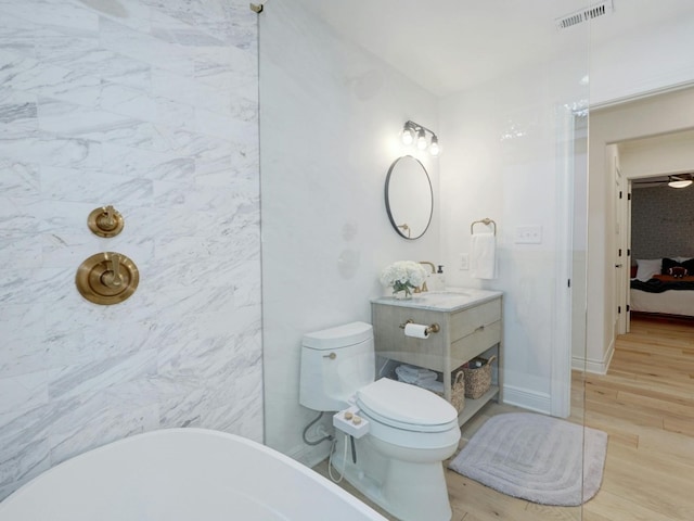 bathroom with vanity, toilet, a bath, and hardwood / wood-style flooring