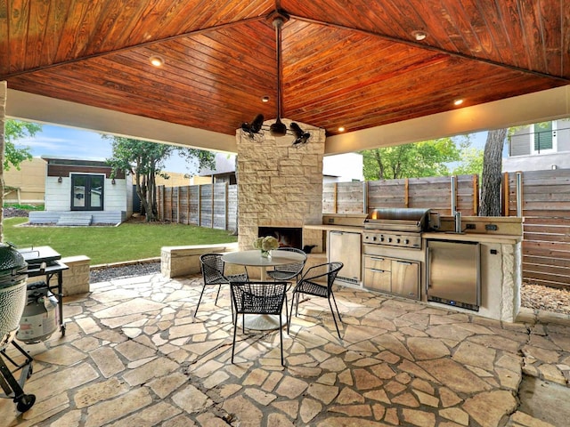 view of patio with an outdoor stone fireplace, area for grilling, and an outdoor kitchen