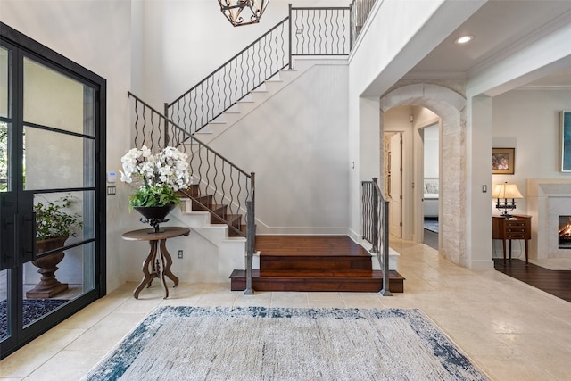 foyer entrance featuring light wood-type flooring, a premium fireplace, and ornamental molding