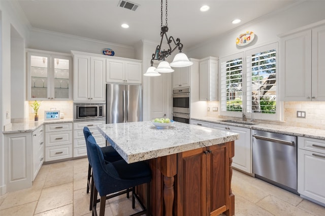 kitchen with white cabinets, appliances with stainless steel finishes, tasteful backsplash, and a kitchen island