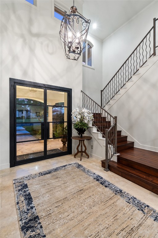 foyer with ornamental molding, a high ceiling, and a chandelier