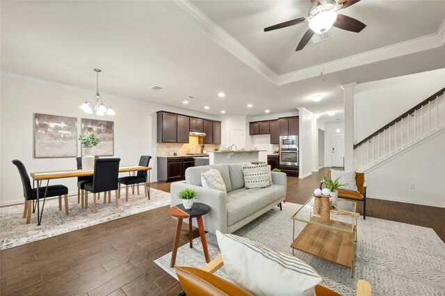 living room featuring crown molding, ceiling fan with notable chandelier, and dark hardwood / wood-style flooring