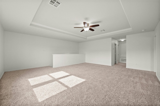 empty room featuring a tray ceiling, ceiling fan, and carpet flooring