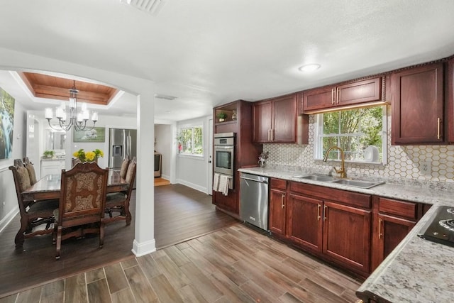 kitchen featuring a raised ceiling, appliances with stainless steel finishes, baseboards, and a sink