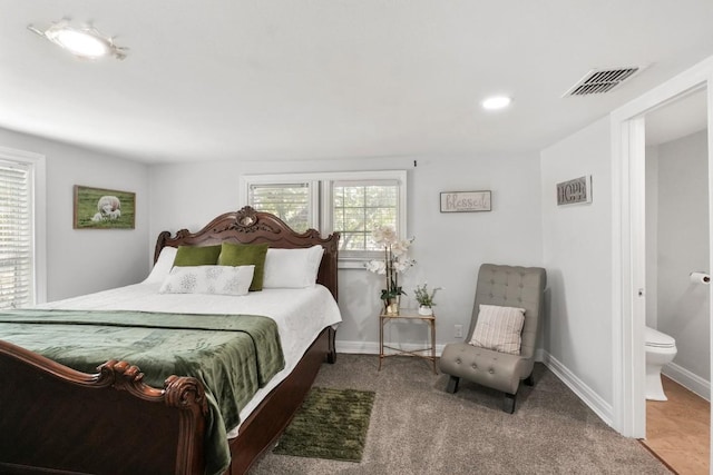 carpeted bedroom with baseboards, ensuite bathroom, and visible vents