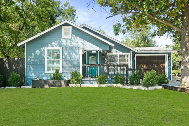 rear view of house with covered porch, a garage, and a yard