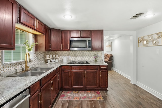 kitchen with decorative backsplash, sink, wood-type flooring, and appliances with stainless steel finishes