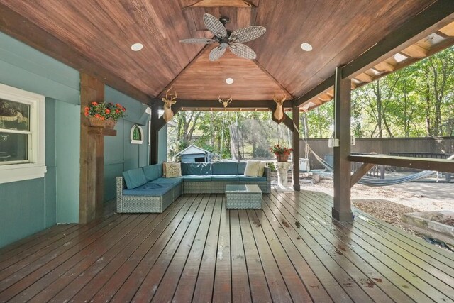 wooden deck with an outdoor living space, a ceiling fan, and fence