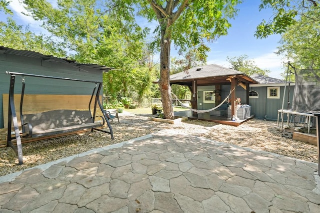 view of patio featuring central AC unit, a gazebo, fence, and a trampoline