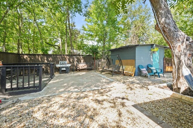 view of yard with a storage unit, an outbuilding, a patio, and fence