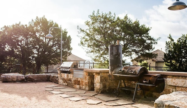 view of patio with exterior kitchen, grilling area, and fence