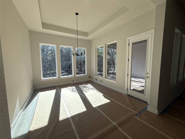 unfurnished dining area with a raised ceiling and a notable chandelier