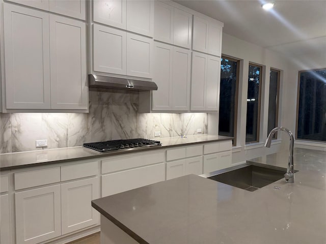 kitchen with backsplash, stainless steel gas cooktop, sink, and white cabinets