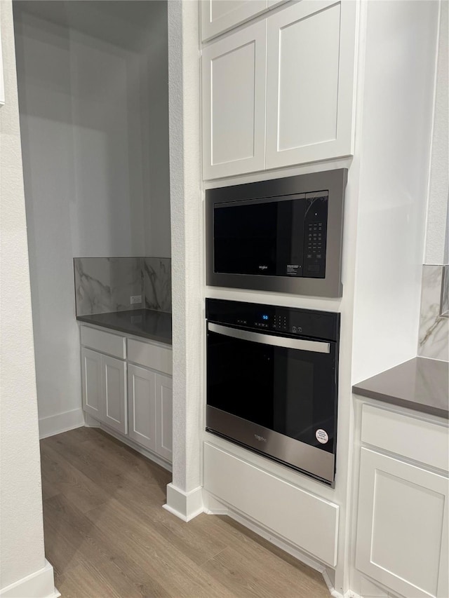 kitchen with built in microwave, oven, and white cabinets