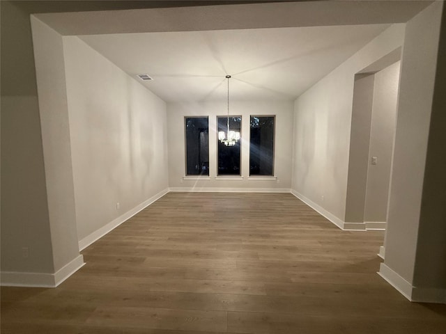 unfurnished dining area featuring hardwood / wood-style floors and a notable chandelier