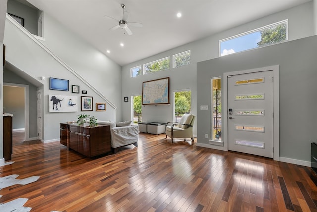 living room featuring ceiling fan, dark wood-type flooring, a high ceiling, and a wealth of natural light