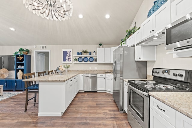 kitchen with white cabinets, appliances with stainless steel finishes, a kitchen bar, kitchen peninsula, and a chandelier