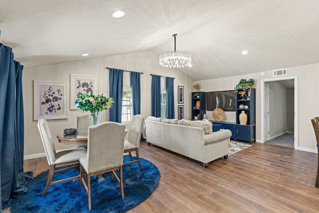 dining area featuring a notable chandelier, wood-type flooring, and vaulted ceiling