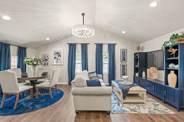 living room with hardwood / wood-style floors, an inviting chandelier, and lofted ceiling