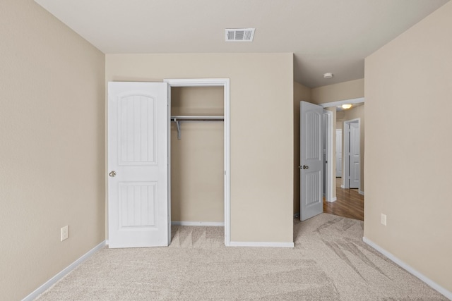 unfurnished bedroom with light colored carpet and a closet