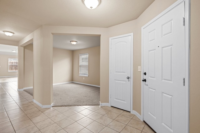 tiled entrance foyer with a textured ceiling and a healthy amount of sunlight