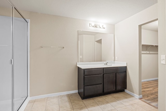 bathroom featuring walk in shower, vanity, hardwood / wood-style floors, and a textured ceiling