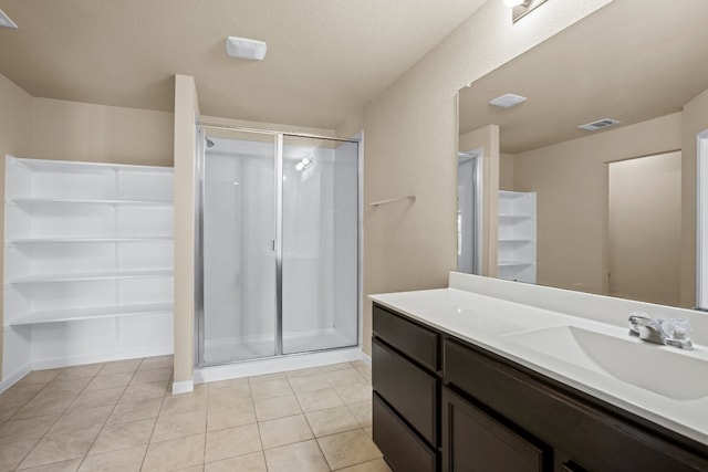 bathroom with a shower with door, vanity, and tile patterned floors