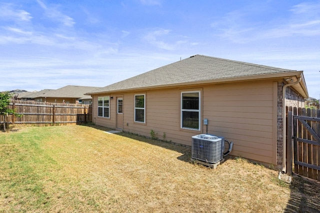 back of property with a lawn and central AC