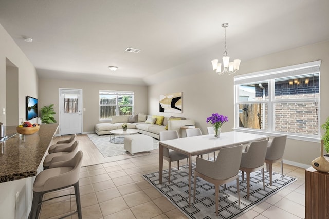 dining area featuring light tile patterned floors and a notable chandelier