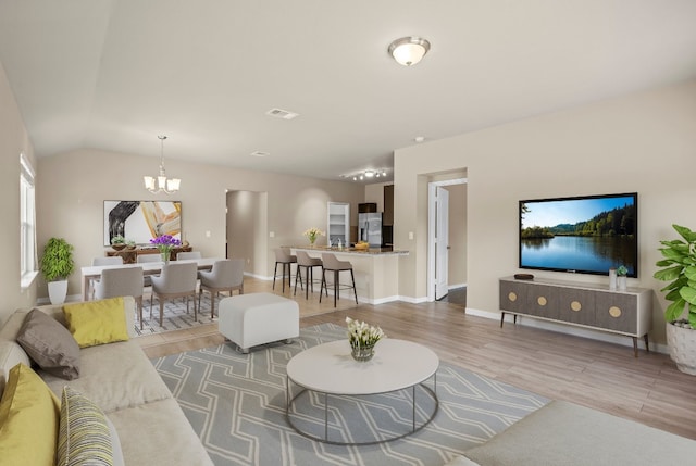 living room featuring wood-type flooring, a notable chandelier, and lofted ceiling