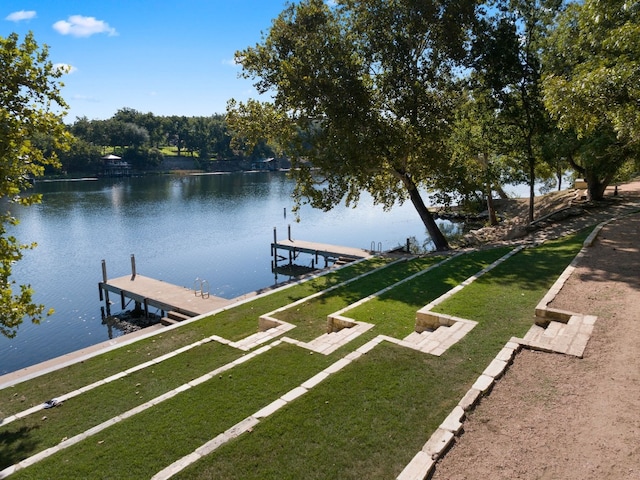 view of dock with a yard and a water view
