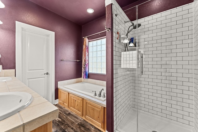 bathroom featuring a shower stall, a garden tub, a sink, and wood finished floors