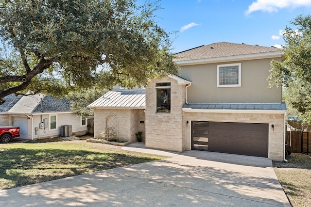 traditional home featuring stone siding, an attached garage, metal roof, concrete driveway, and a standing seam roof