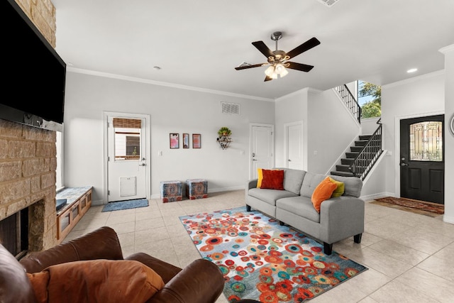 living area featuring a ceiling fan, ornamental molding, visible vents, light tile patterned flooring, and stairway