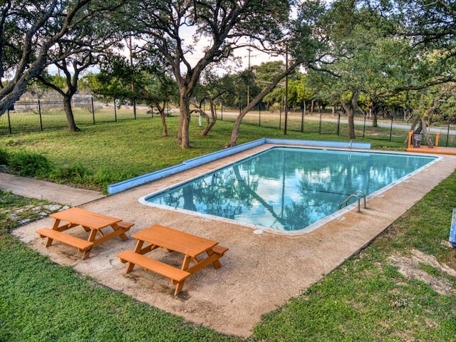 community pool featuring fence and a lawn