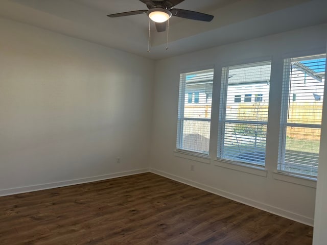 spare room featuring dark hardwood / wood-style floors, ceiling fan, and a healthy amount of sunlight