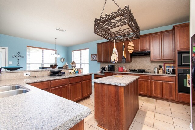 kitchen with light tile patterned flooring, tasteful backsplash, decorative light fixtures, black appliances, and a center island