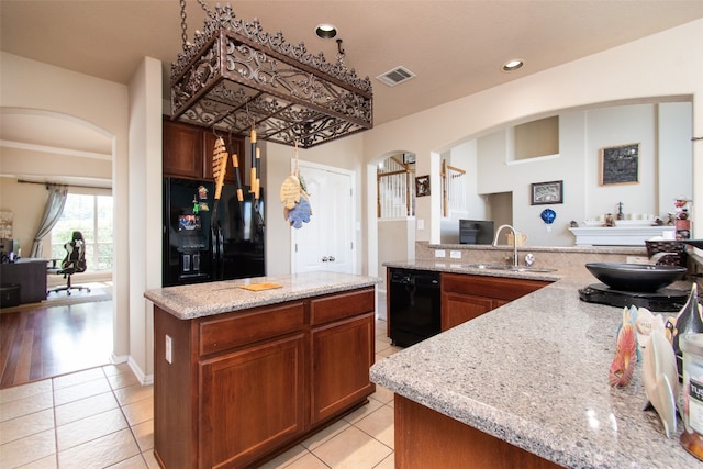 kitchen featuring light hardwood / wood-style floors, light stone countertops, black appliances, a center island, and sink