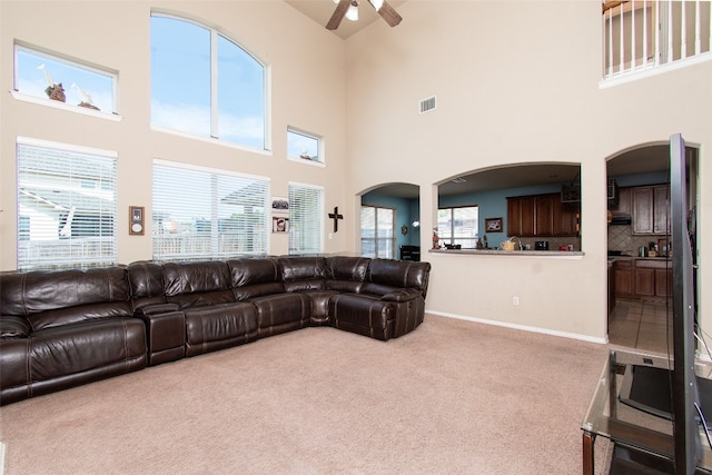 carpeted living room with high vaulted ceiling, a wealth of natural light, and ceiling fan