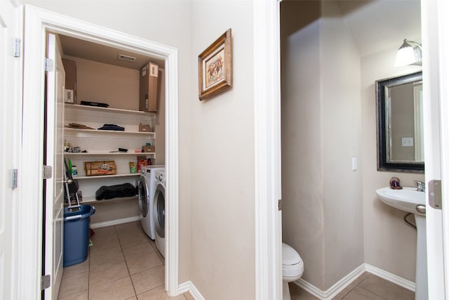 bathroom featuring toilet, tile patterned flooring, and washing machine and dryer