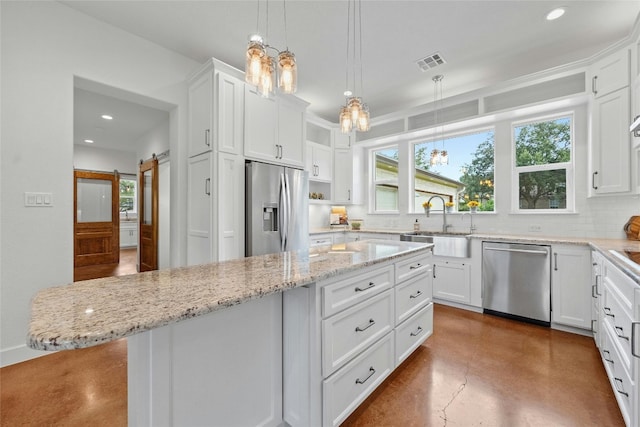 kitchen featuring plenty of natural light, white cabinetry, a kitchen island, a barn door, and appliances with stainless steel finishes