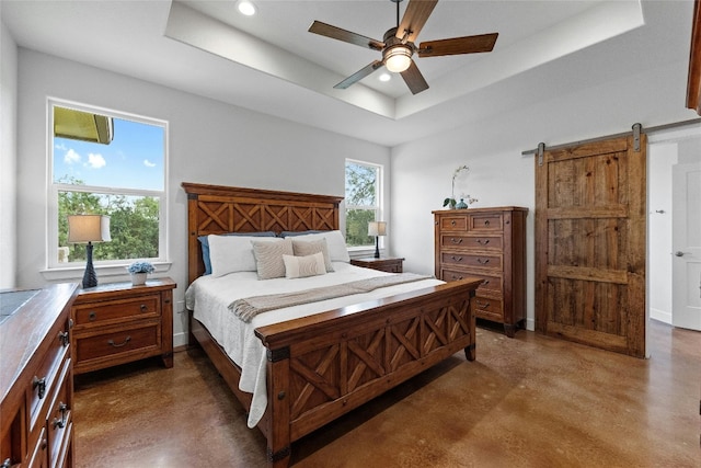 bedroom with a tray ceiling, ceiling fan, and a barn door