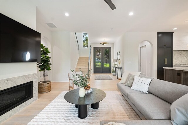 living room with a premium fireplace, french doors, and light wood-type flooring