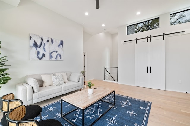 living room with a towering ceiling, a barn door, and hardwood / wood-style flooring